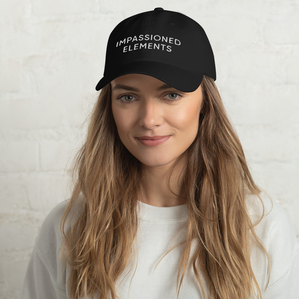 A woman sporting a black dad hat with the words Impassioned elements embroidered on it