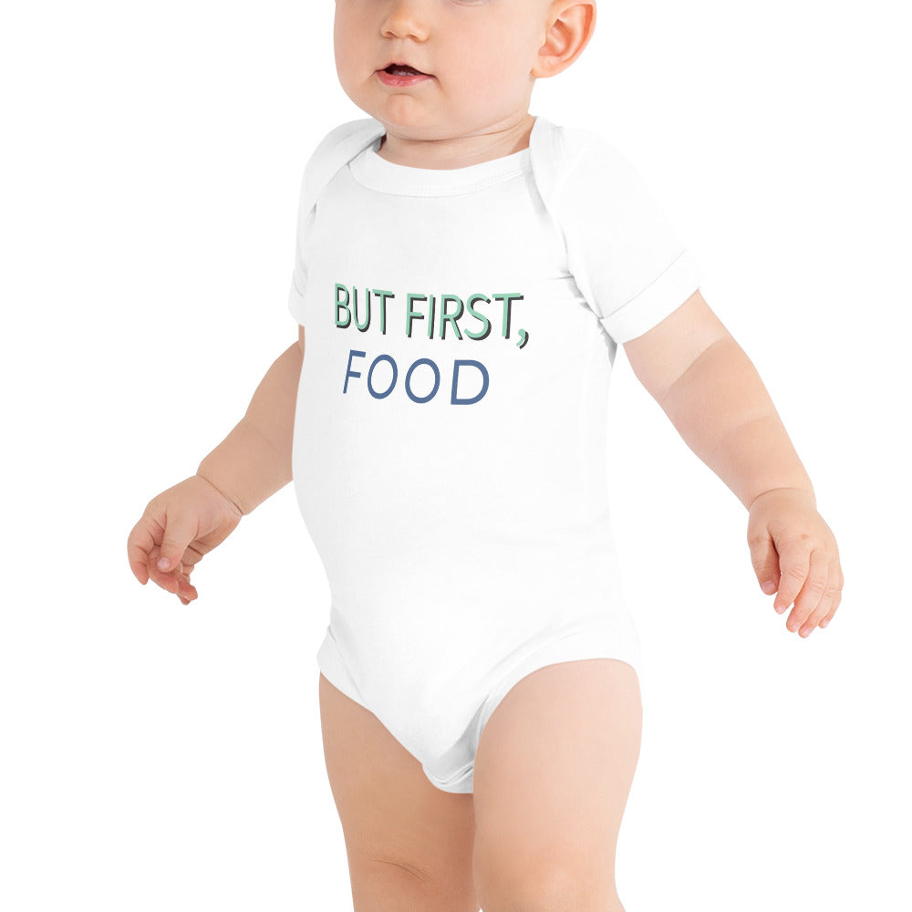 Cute baby wearing a white bodysuit that says "but first food." Perfect for foodie parents. Get it now!