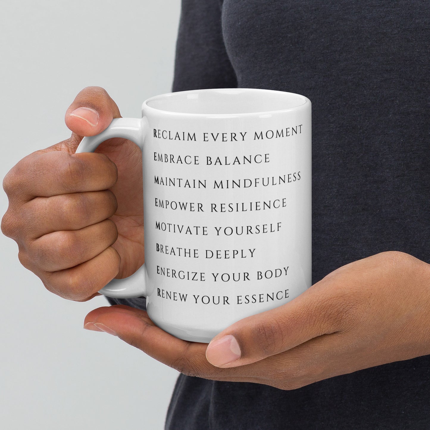 Man holding a 15 oz reclaim every moment mental health coffee mug