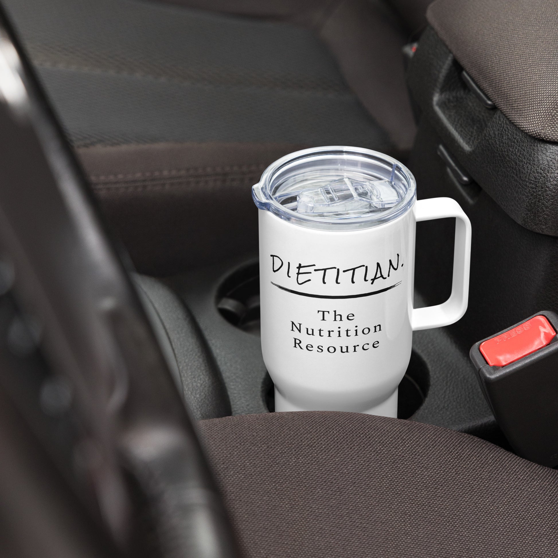 A white travel mug with the words "Dietitian. The Nutrition Resource" proudly displayed sitting in a drink holder of car.