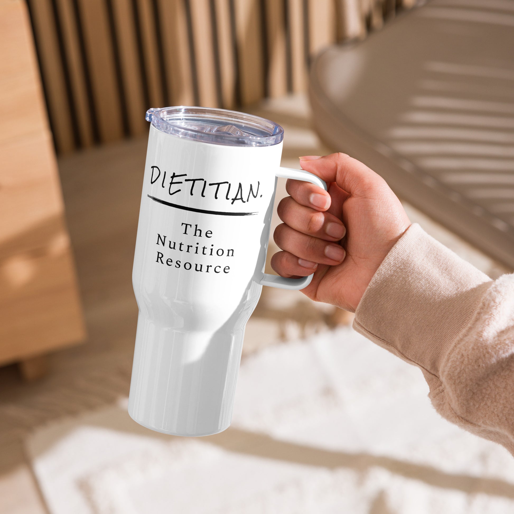 A women holding a white travel mug with the words "Dietitian. The Nutrition Resource."